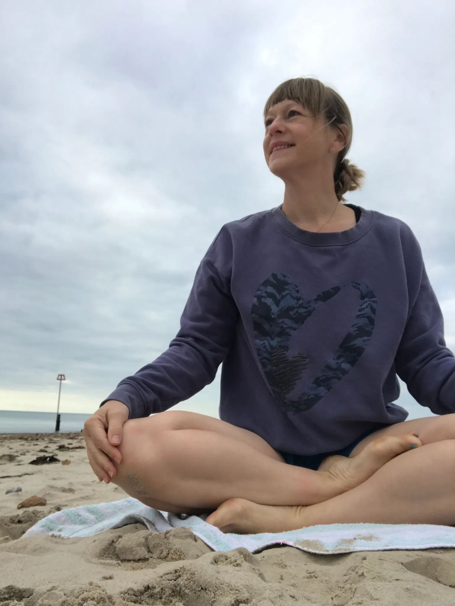 Claire sitting cross-legged on the beach